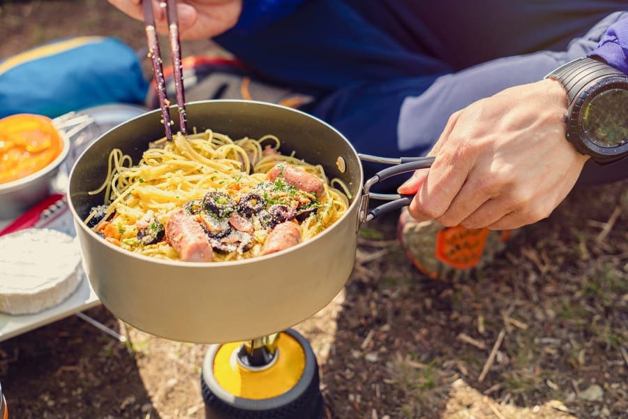 Preparing noodles with cooking utensil on camping stove